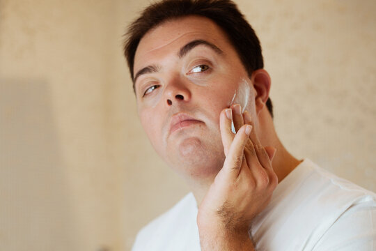 Young Man With Down Syndrome Applying Shaving Cream In The Bathroom