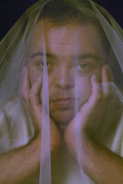 Closeup portrait of young man with Down Syndrome underneath veil