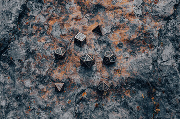 An image of a metallic set of RPG dice on a rocky surface