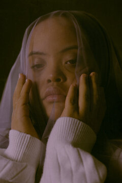 Closeup portrait of young biracial woman with Down Syndrome underneath veil