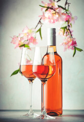 Rose wine glass and bottle on the gray table and pink flowers. Rosado, rosato or blush wine tasting