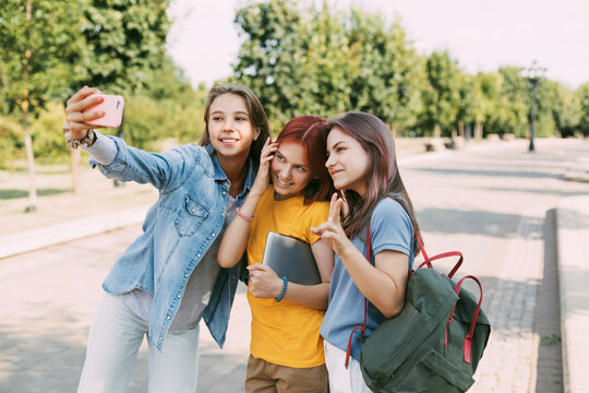 Three charming friends take selfies with their phone on the way to school. The concept of friendship. Education, training, back to school