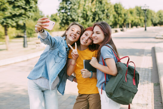 Three charming friends take selfies with their phone on the way to school. The concept of friendship. Education, training, back to school