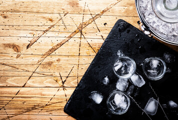 Russian vodka in shot glasses on wooden table, iced strong alcohol drink in misted glass. Top view, negative space