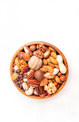 Nut mix in bowl. Almonds, hazelnuts, walnuts and other. Healthy food snack mix on white table, top view, copy space