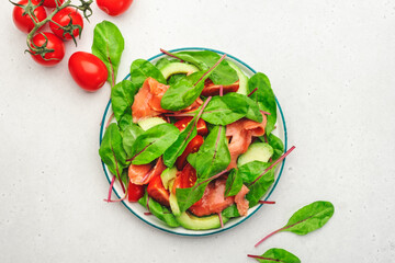 Salmon avocado salad, beet leaves, radicchio, tomatoes, lemon and olive oil dressing for keto and low card diet. Gray background, top view