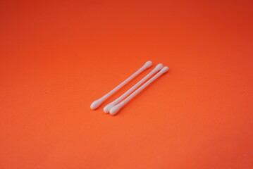 Stock photo of a pile of white cotton buds that are lined up and neatly arranged so that it looks aesthetic. Isolated on an orange background. Medical equipment Industry,design,website photo,Pattern