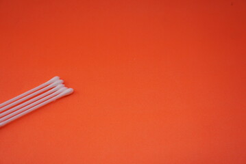 Stock photo of a pile of white cotton buds that are lined up and neatly arranged so that it looks aesthetic. Isolated on an orange background. Medical equipment Industry,design,website photo,Pattern
