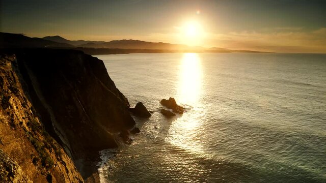 Timelapse. Sunset over rocky cliffs at Asturias coast in north Spain. View from Faro de Cabo Busto. Tourist attraction, place to visit.