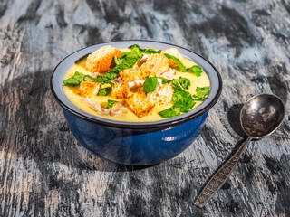 Puree soup with chicken meat and toasted croutons in a blue plate