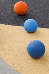Fototapeta na wymiar Three stone color balls: light blue, dark blue, orange on asphalt and grey textured artificial ground. Background or backdrop.