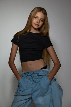 beautiful girl teenager in jeans and a black t-shirt posing in the studio on a light background 