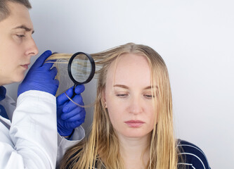 A trichologist examines a girl with oily hair. Problematic scalp and increased secretion of the...