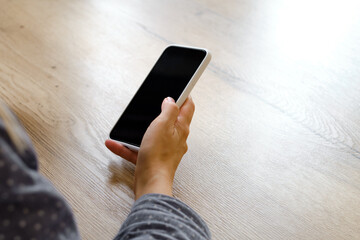 A girl is holding a modern smartphone, sending a text message or using an application on her mobile phone. Gadget addiction. Smartphone close-up. Focus on the phone screen