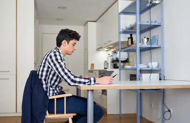 profile of a young man who is teleworking in the kitchen of home