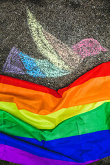 dove of peace painted with chalk on the street, under it the rainbow flag