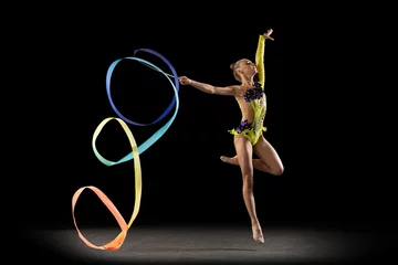 Foto op Canvas One sportive emotional girl, rhythmic gymnastics artist isolated on dark background in ray of light. Concept of sport, action, aspiration, beauty, active lifestyle © master1305