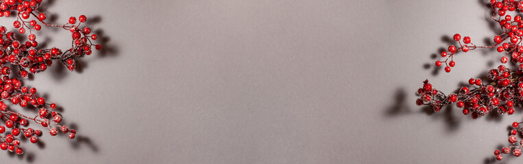 Banner of red berries on the branch Christmas decoration on gray background on the left and right side. Top view flat lay. Holidays concept with copy space