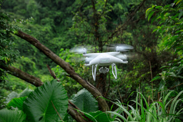 White drone with camera flying in summer forest