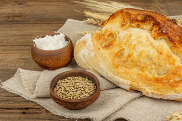 Freshly baked bread with wheat ears, a bowl of grain and flour