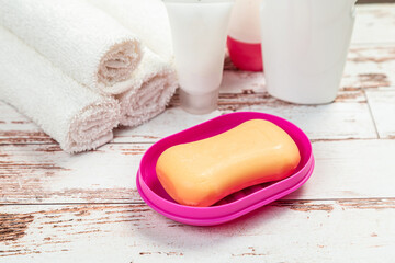 soap on pink plastic soap dish with towels on white wooden table in bathroom