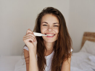 smiling woman holding thermometer in bedroom mouth checking temperature