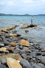 Fototapeta na wymiar Asian woman standing on large stone on the beach