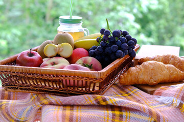beautiful summer still life, fruits, grapes, peaches, apples, croissants, green trees in the background, concept picnic in nature, summer vacation, healthy eating