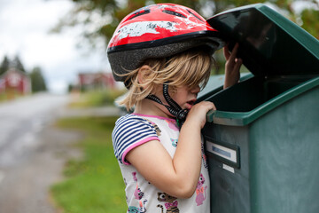 Child with red bike helmet checking the mailbox