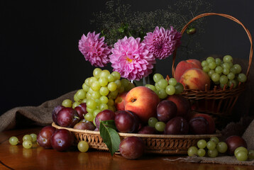 Still life with fruits and a bouquet of summer flowers on a dark background