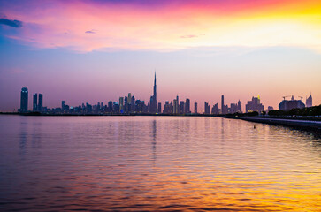Fototapeta na wymiar Stunning view of Dubai city skyline at sunset with a colorful sky and reflection on the water. Al Jaddaf, Dubai, UAE.