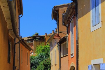 Fototapeta na wymiar A popular tourist holiday destination, beautiful French village in Provence called Roussillon with its ancient houses and buildings, old ochre-colored roofs and walls, and relaxed summer vibes.