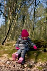 Little girl having fun in beautiful forest with dry yellow leaves and green moss