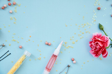 Cosmetic products, accessories, brushes for makeup and powder. Flowers decorations. Beauty concept. Top view, copy space blue background