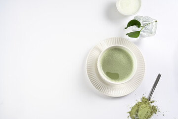 A white porcelain cup with japanese matcha tea drink on a white saucer plate on a white surface, a...