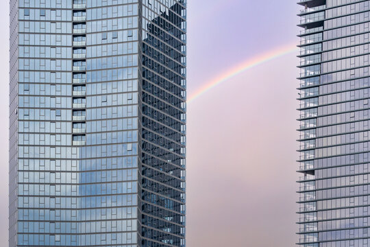 Horizontal shot of a rainbow between two high rise buildings with window mirrors