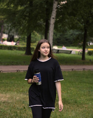 young sports girl with a glass of water or sports drink in the park outdoors, healthy lifestyle