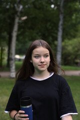 young sports girl with a glass of water or sports drink in the park outdoors, healthy lifestyle