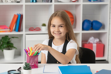 happy child taking stationery at school lesson in classroom wear uniform, study