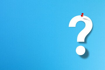 Question mark and red thumbtack with copy space on blue background	