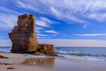 Sawtooth rock monolith stands away from the shoreline as erosion takes its toll on the red stone cliffs as waves crash on the shoreline