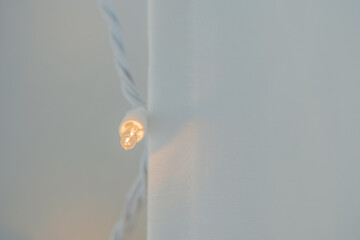 Horizontal image of Soft linen curtains covering soft white  lights inside a home making for a...