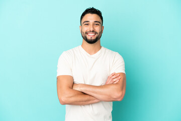 Young arab man isolated on blue background keeping the arms crossed in frontal position