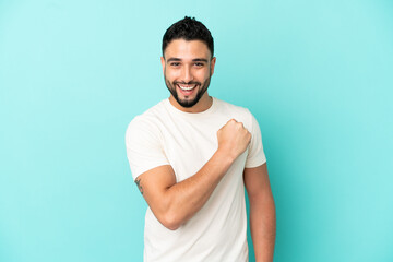 Young arab man isolated on blue background celebrating a victory