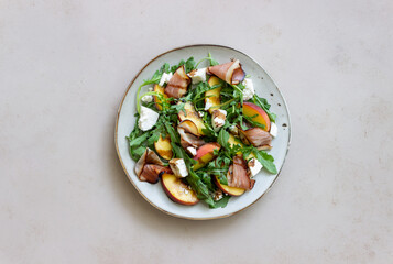 Salad with peaches, arugula, cheese and jamon. Healthy eating.