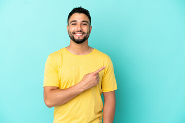 Young arab man isolated on blue background pointing to the side to present a product