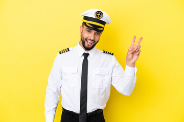 Airplane arab pilot man isolated on yellow background smiling and showing victory sign