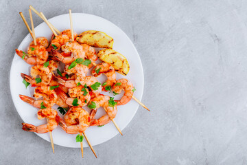 Grilled Lemon Shrimp Skewers in plate on gray stone background.