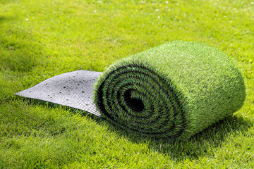 rouleau de pelouse synthétique sur pelouse naturelle
