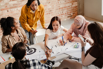 Multiracial young feminist women making posters during meeting